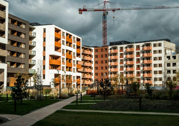 Newly built residential buildings under cloudy skies with a construction crane.